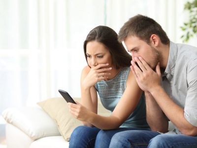 Worried couple reading news on smartphone